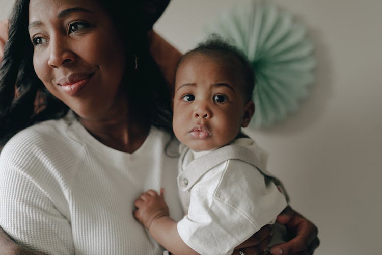 Portrait Of Happy Woman Holding Baby In Hands