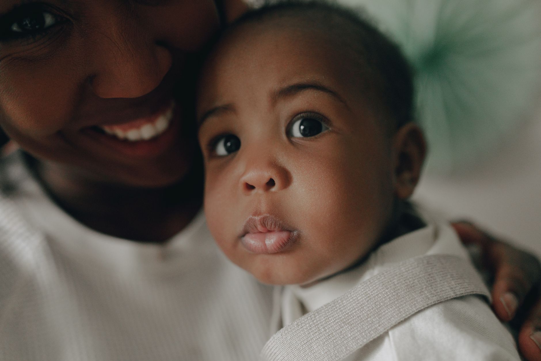 2025 청년지원금 조건 완화 및 변경 사항 6 African American mother lovingly holds her baby, showcasing a close-up of faces filled with tenderness.
