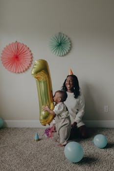 A joyful moment of a mother and her toddler holding a gold balloon to celebrate his first birthday.