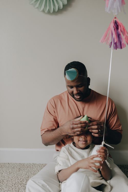 Free A father and child having fun with party hats during a birthday celebration indoors. Stock Photo