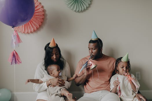 Happy family celebrating a child's first birthday with party hats and decorations indoors.