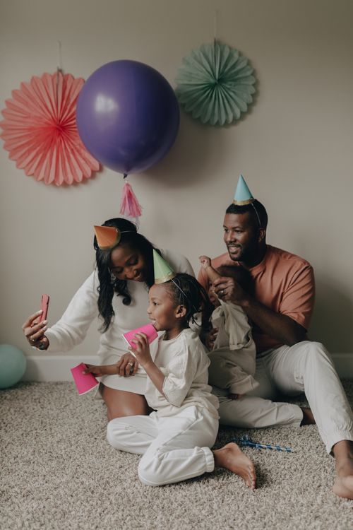 Free A happy family celebrating a birthday with party hats and decorations indoors. Stock Photo