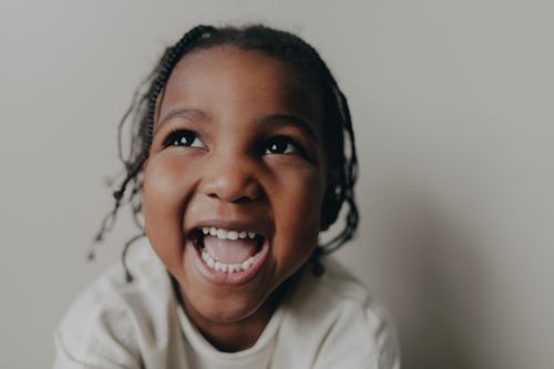Free Happy young girl with braided hair smiling joyfully in a close-up shot. Stock Photo