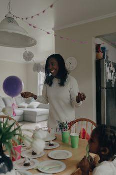Smiling woman and child at a cheerful birthday party with balloons and cake.