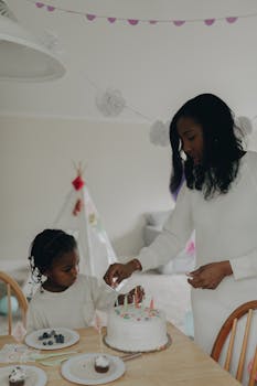 A mother and daughter celebrate a birthday together with a cake and decorations.