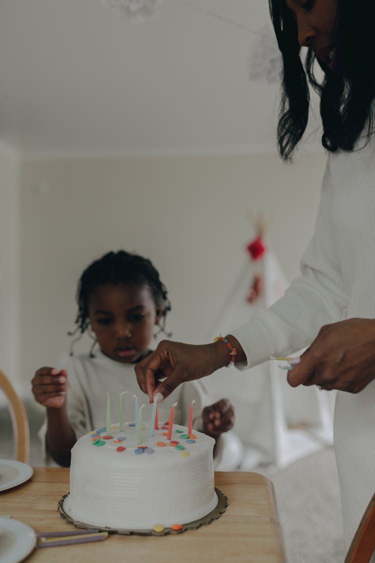 A Woman Putting Candles On A Birthday Cake