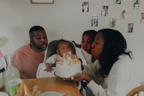 Free Family with Two Children Blowing Out the Candles on a Birthday Cake  Stock Photo
