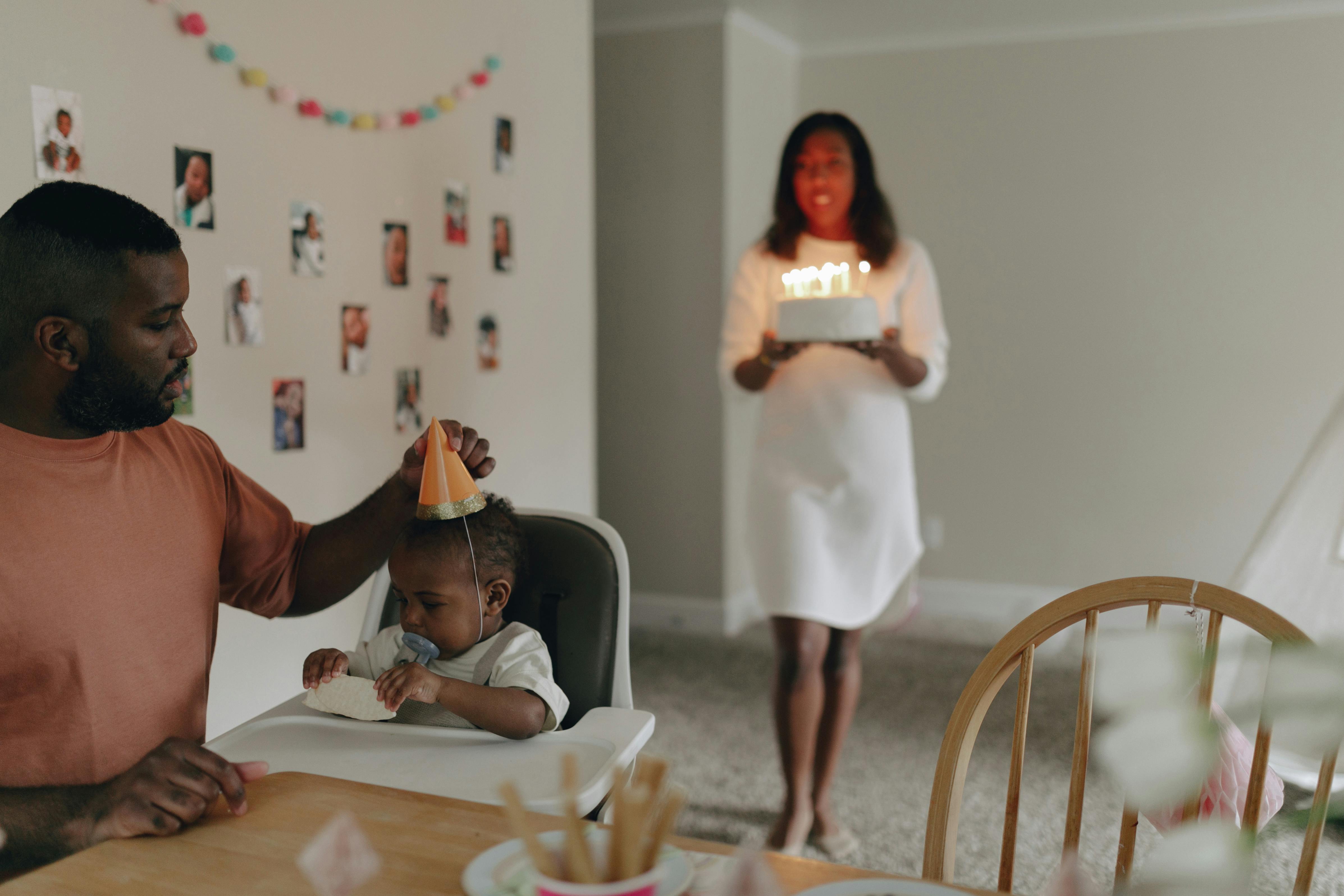 A joyful family celebrating a baby's first birthday with cake and decorations.