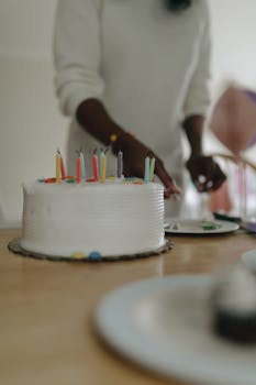 Celebration with a decorated birthday cake and colorful candles on a wooden table.