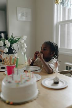A child enjoys a birthday celebration at home with cake and decorations.