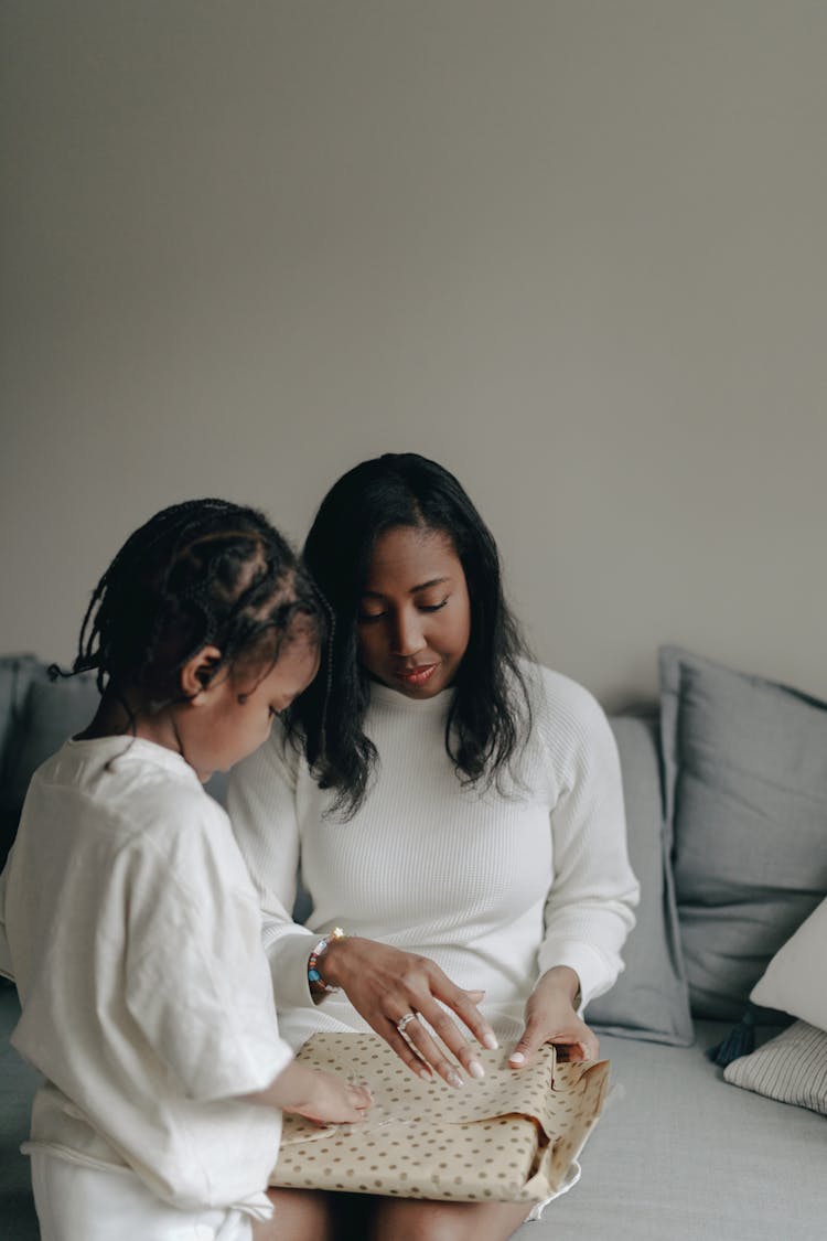 A Mother And Her Daughter Unwrapping A Gift