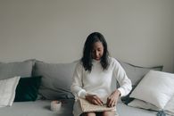 Woman in White Long Sleeve Shirt Sitting on Gray Couch