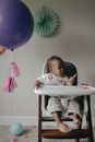 Baby in Jumper Sitting on White High Chair