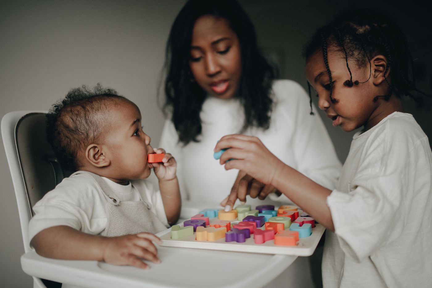 A parent and children using colorful learning toys together at home