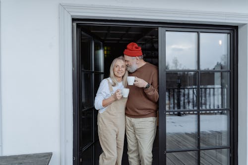 Man and Woman Standing by the Door Holding Mugs