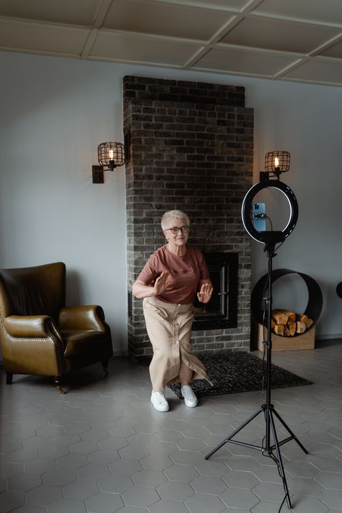 Free Elderly woman joyfully dancing in a cozy living room with a modern setup. Stock Photo