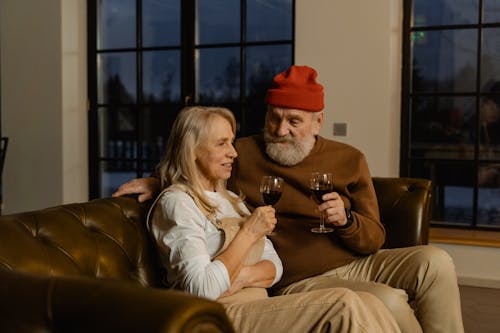 Free People Sitting on a Couch Holding Wine Glasses Stock Photo