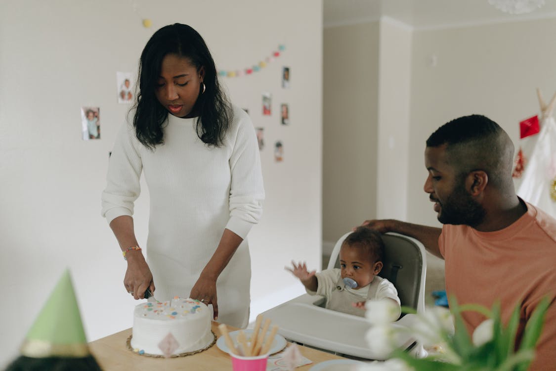 Free Woman Slicing the Cake While the Man and Child is Looking at Her  Stock Photo