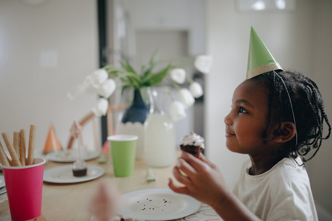 Kid Wearing Party Hat Holding a Cupcake