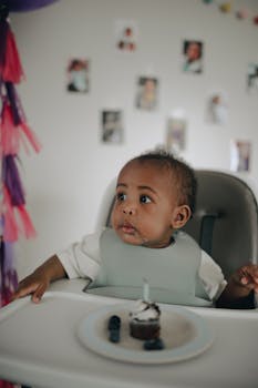 Cute African American toddler enjoying a cupcake on their first birthday.
