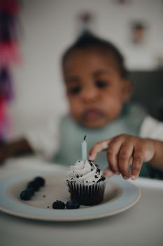 Cute infant enjoying a cupcake with candle at a birthday party, creating a sweet and memorable moment.