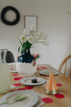 A beautifully set birthday table featuring a vase of white tulips and festive decor.