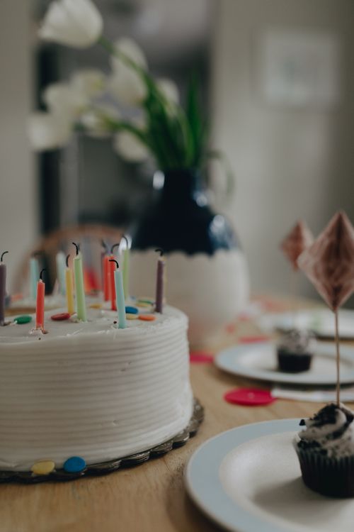 Free Celebrate with a vibrant birthday cake adorned with colorful candles and decorated cupcakes. Stock Photo