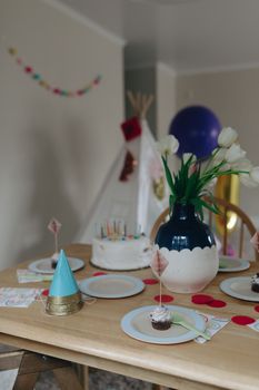 A vibrant birthday party setup indoors featuring a decorated table with cake, cupcakes, and flowers.