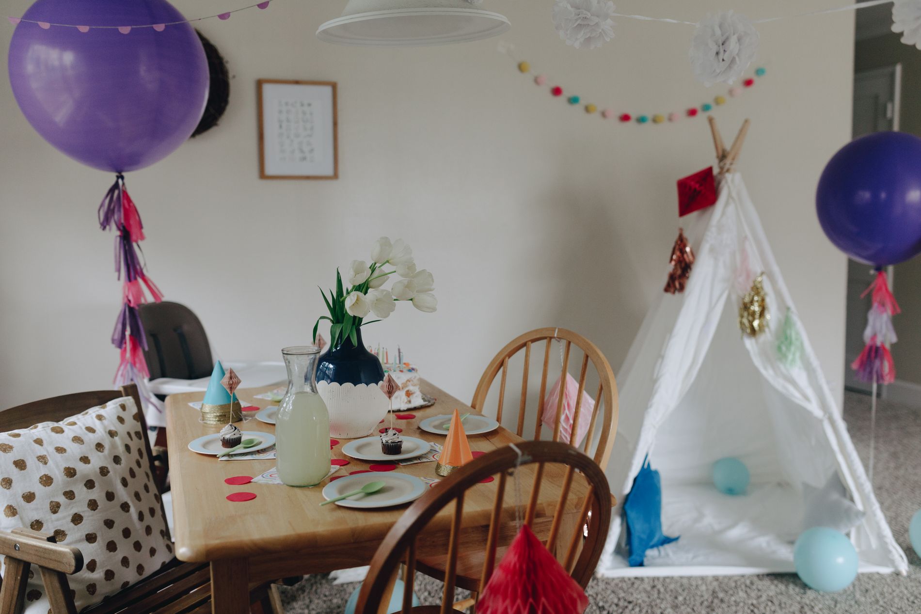 Complete indoor birthday celebration setting with balloons, decorated table, and party accessories