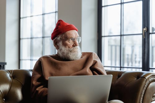 Man Sitting on a Leather Couch Using a Laptop