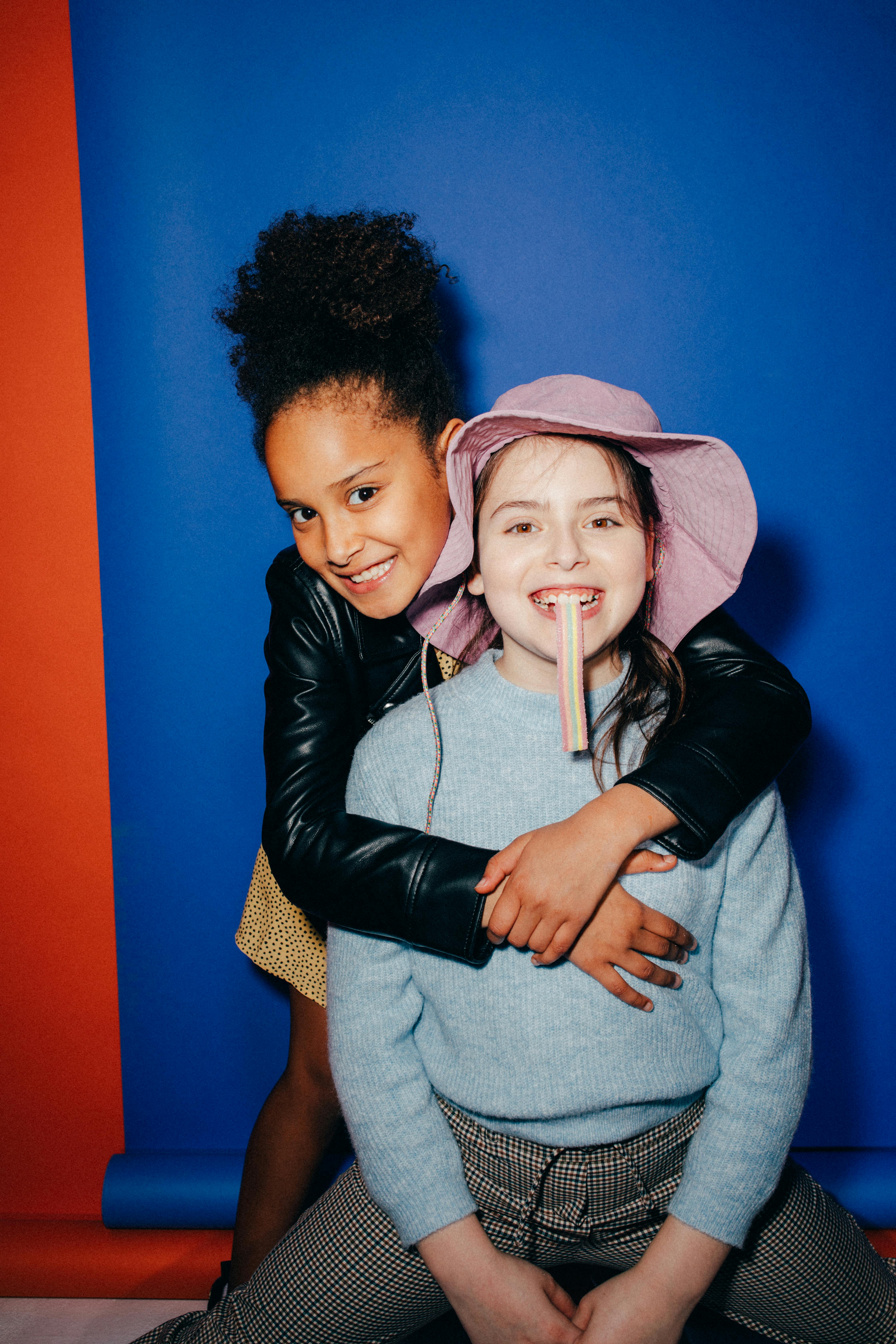 girl in black jacket hugging a girl eating candy