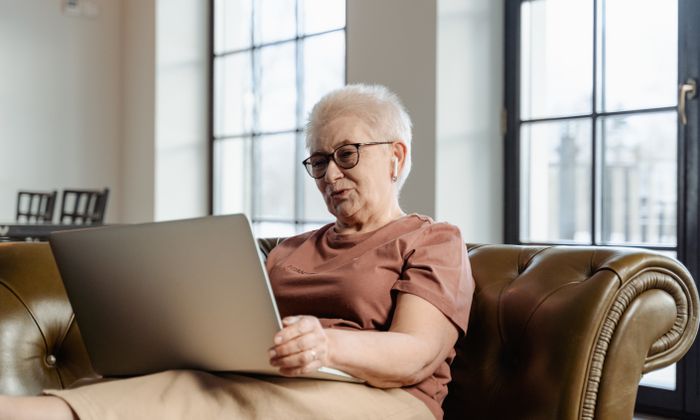 Femeie vârstnică folosind un laptop pe canapea
