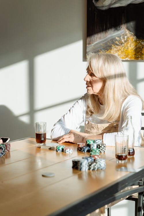 Free Elderly woman engaged in a poker game at home with drinks and chips on the table. Stock Photo