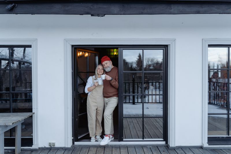 An older couple standing together in the doorway of their home