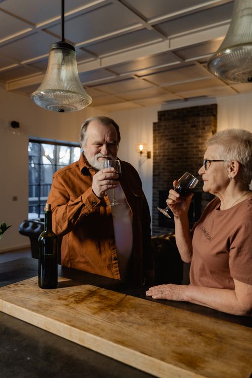 Free Senior couple savoring wine in a cozy home setting, enjoying togetherness. Stock Photo