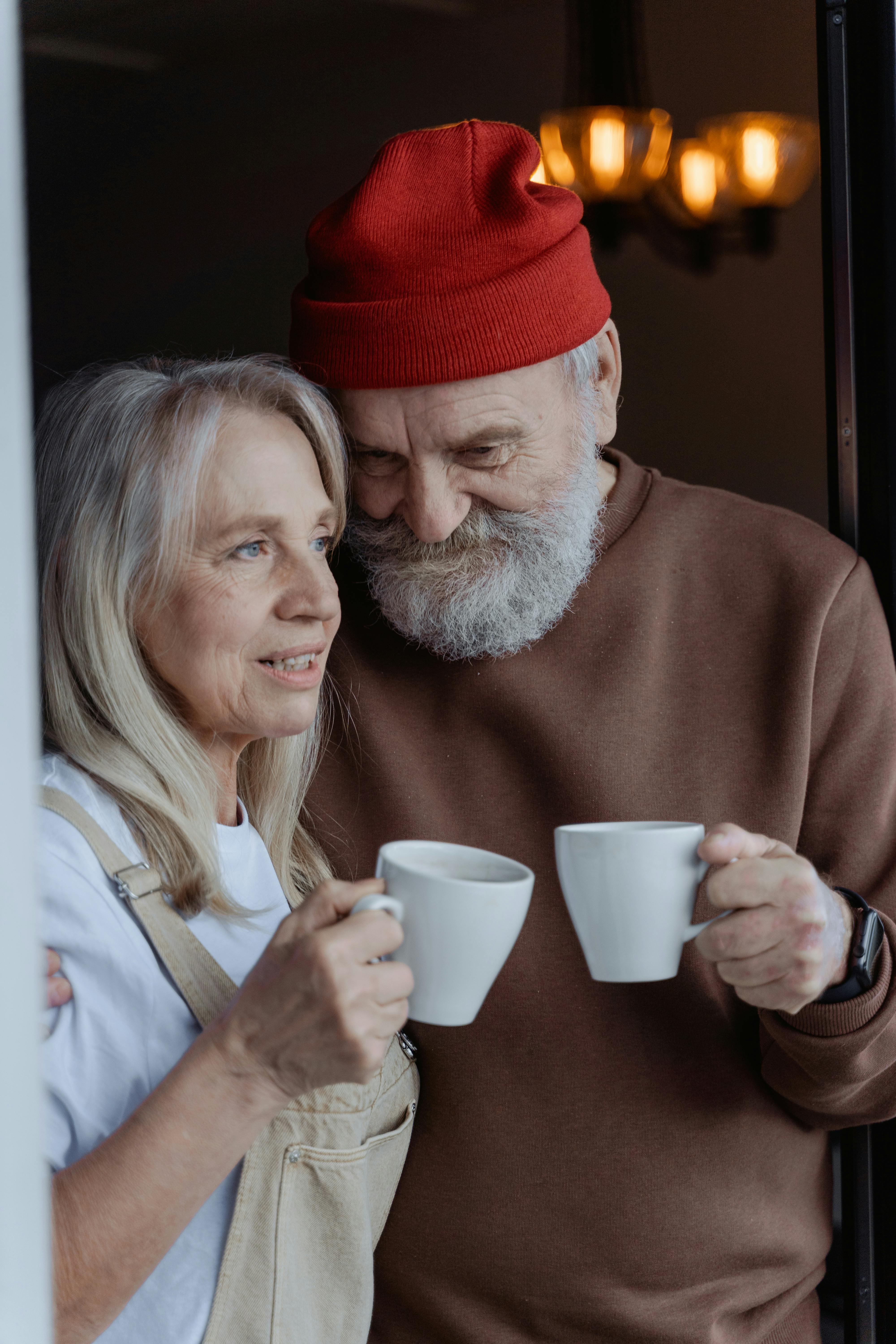 man in red knit cap holding white ceramic mug