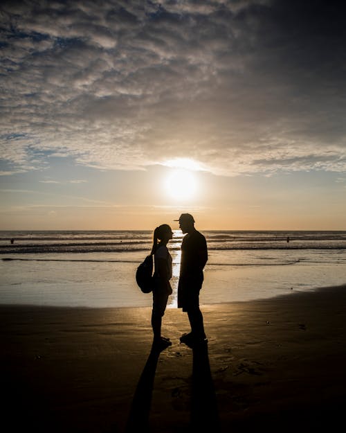 Silhouette of Couple Standing on Beach during Sunset