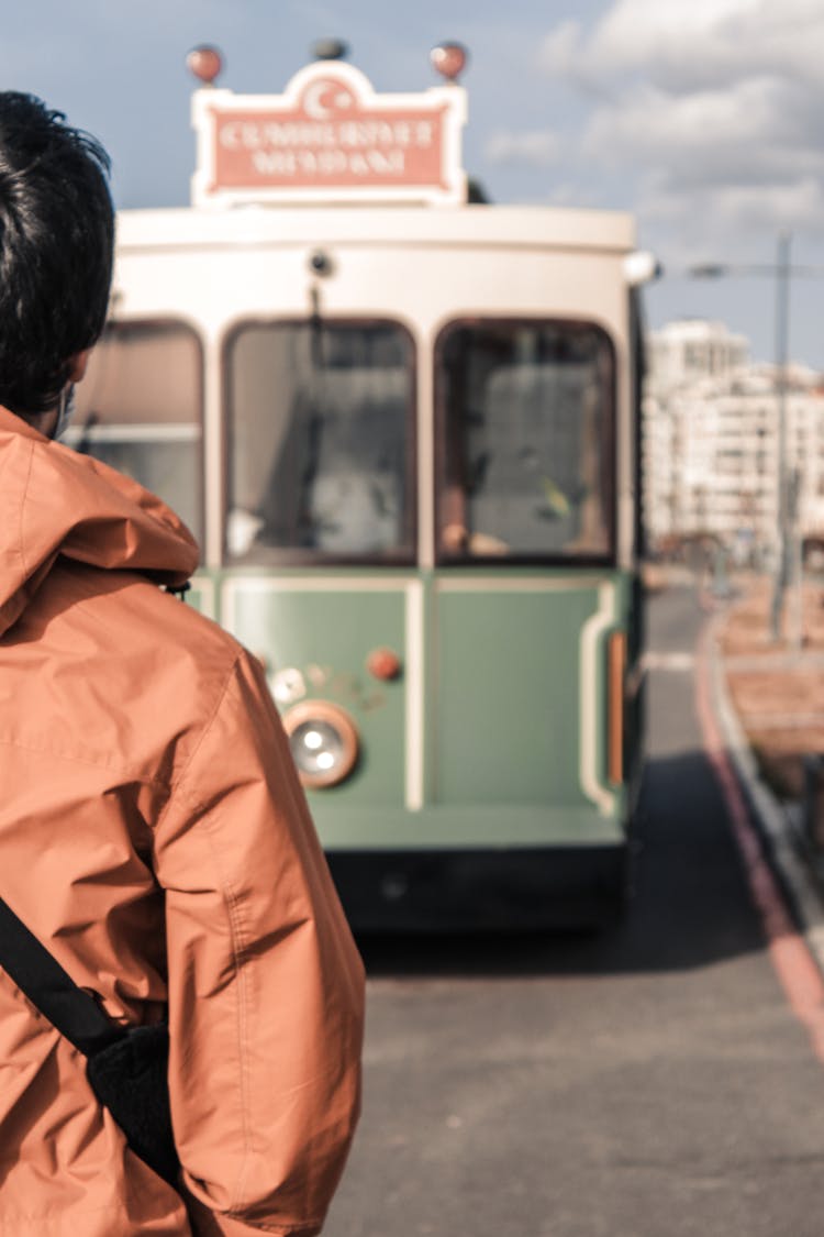 Man In Red Jacket Looking At Old Bus