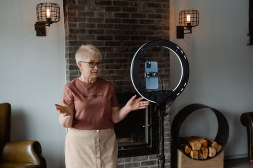 Free Elderly woman using a smartphone for entertainment at home with modern lighting setup. Stock Photo