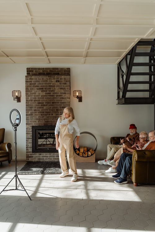 Free A serene living room scene with seniors relaxing by the fireplace and a young woman standing. Stock Photo