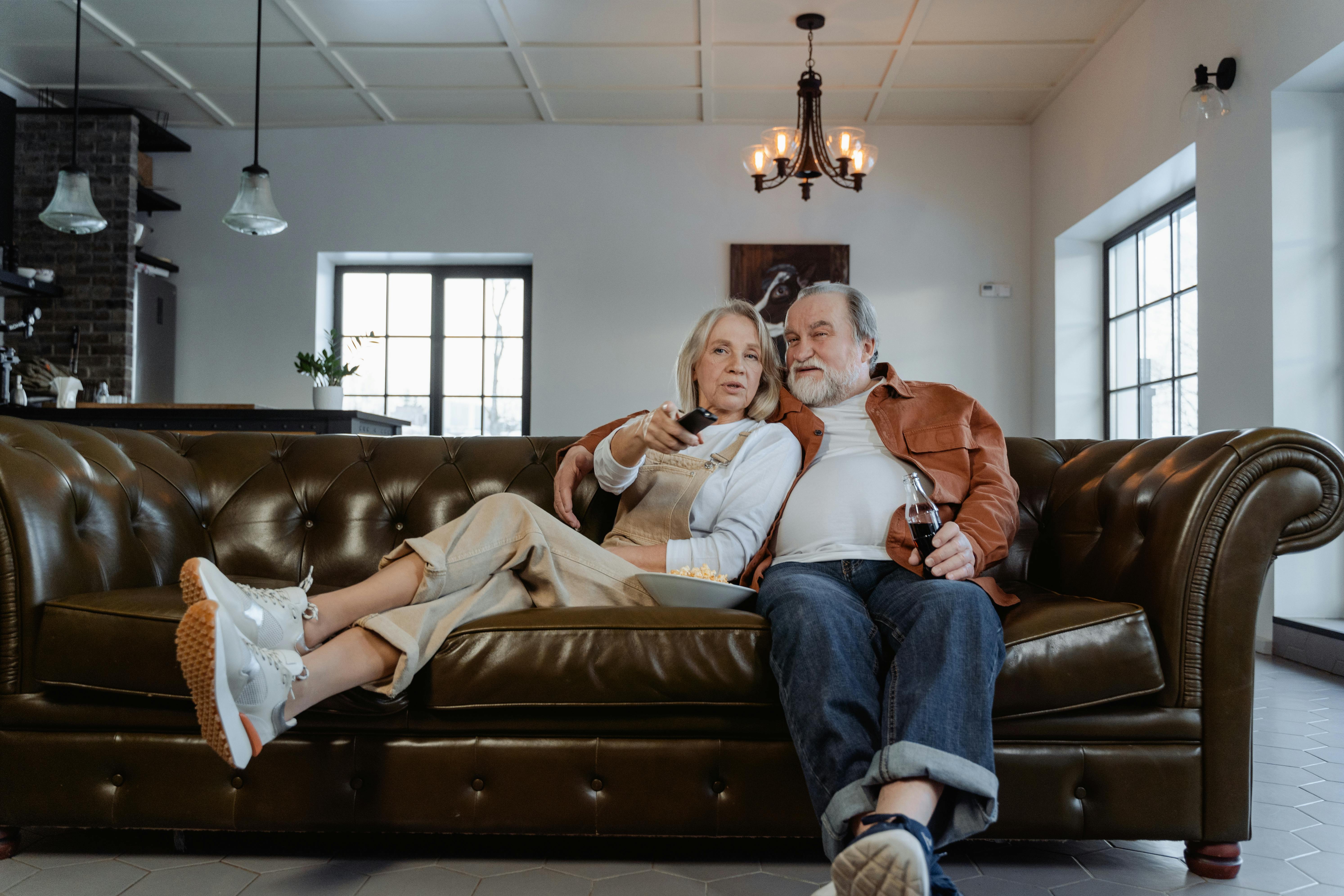 Comfortable elderly couple enjoying a cozy time together at home on a leather sofa.
