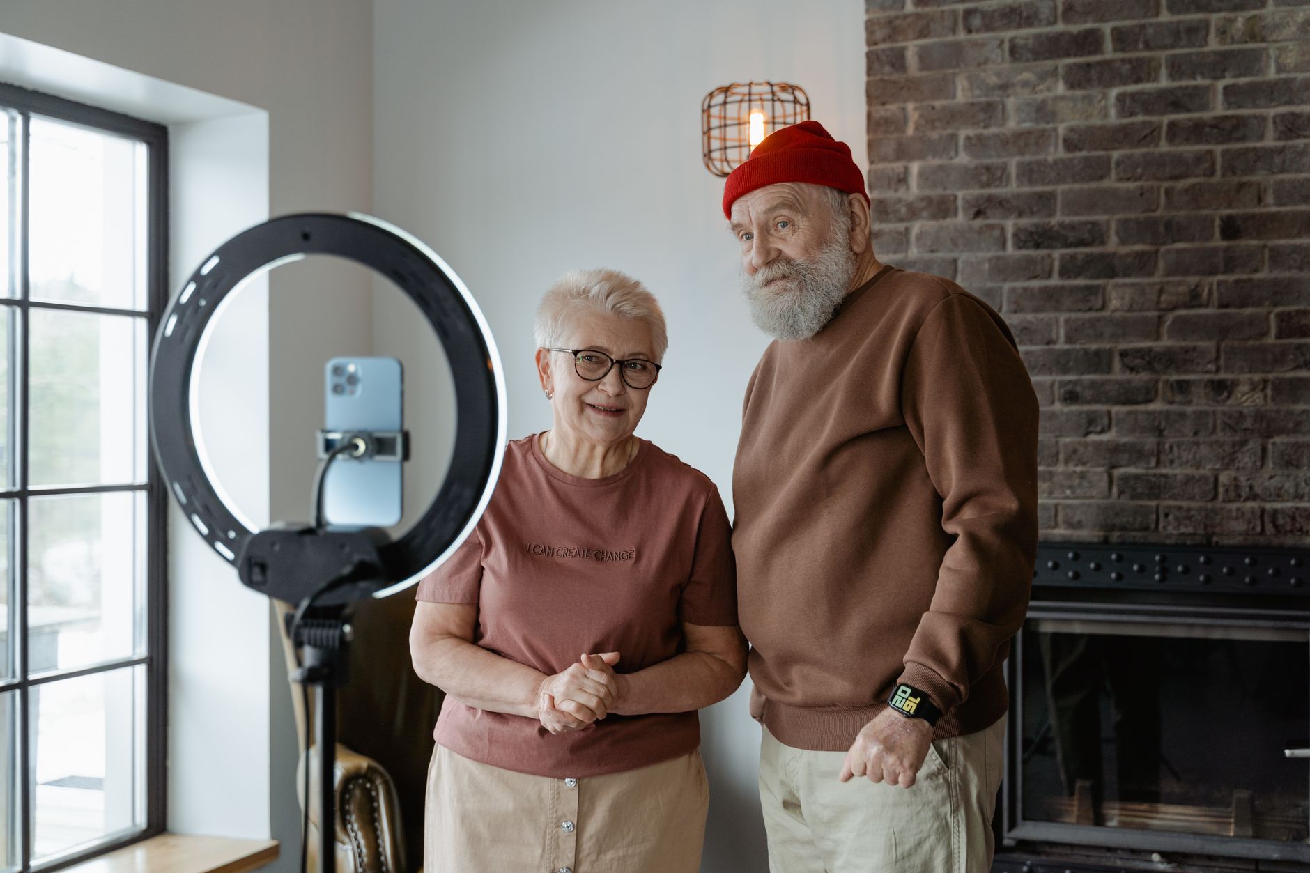 How to Teach Seniors to Use a Smartphone for the First Time A charming elderly couple recording content indoors with a smartphone and ring light.