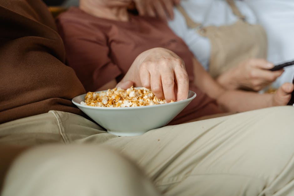 A close-up of people enjoying a cozy evening with a bowl of delicious popcorn.