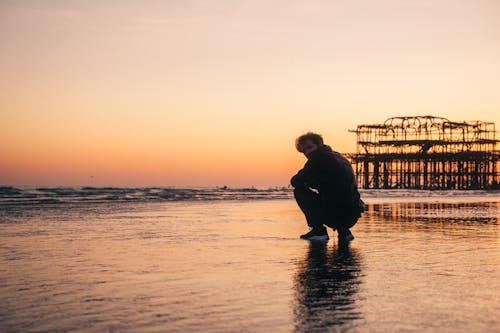 Man Sitting on Beach During Sunset