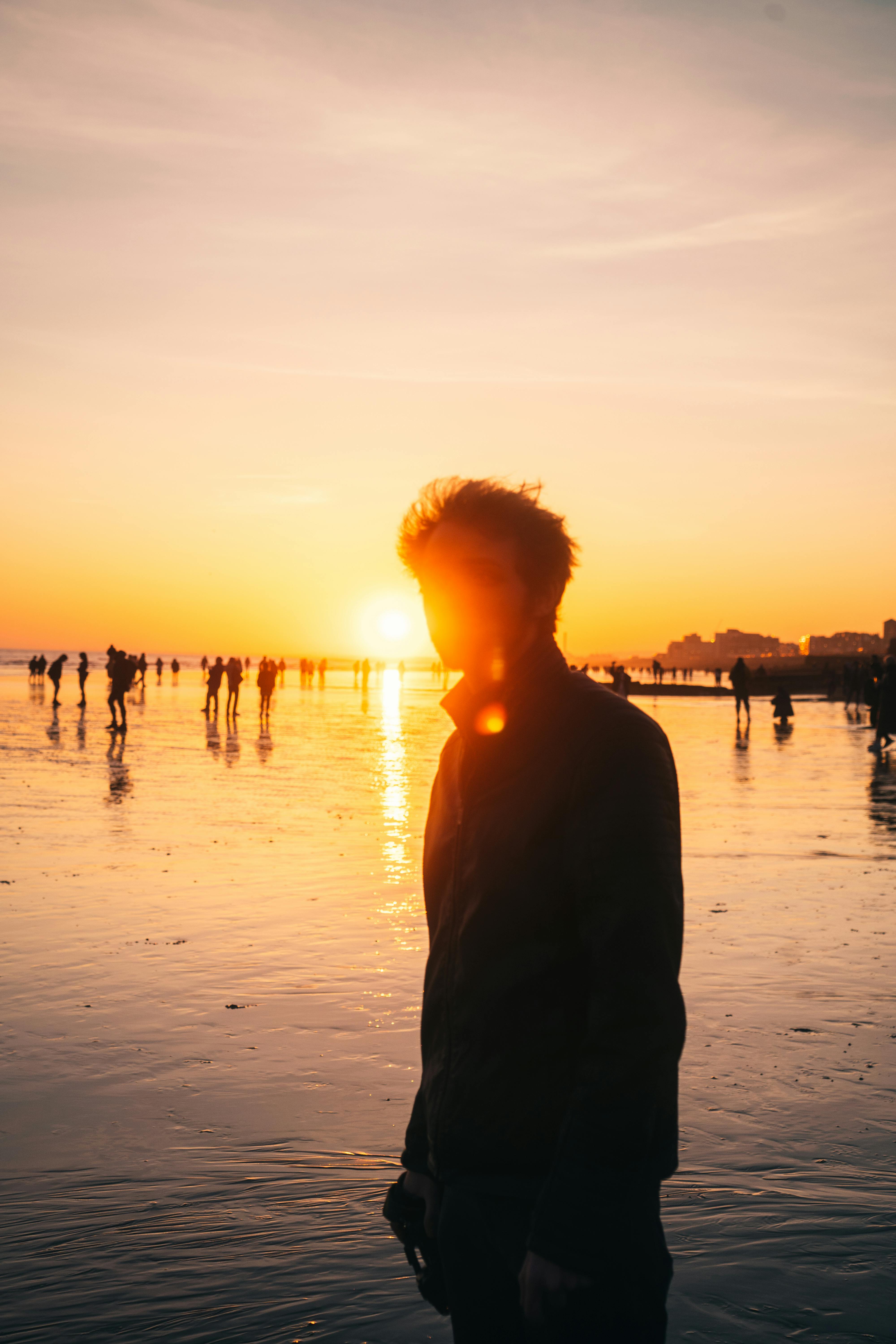 Silhouette of a person at sunset on Brighton Beach, England, with a warm golden hour glow.