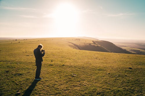 Man in Black Jacket Standing on Green Grass Field