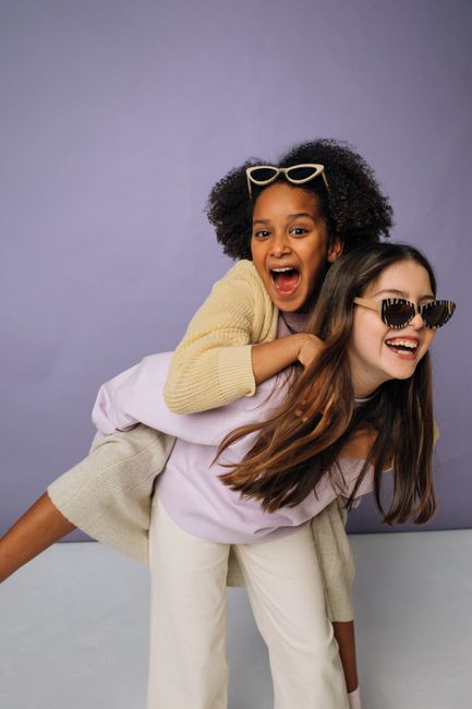Two happy girls enjoying a playful piggyback ride and laughing together.