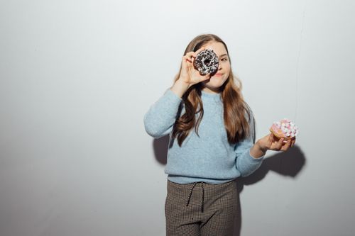 Free A cheerful young girl holding donuts, capturing the joy of sweets. Stock Photo