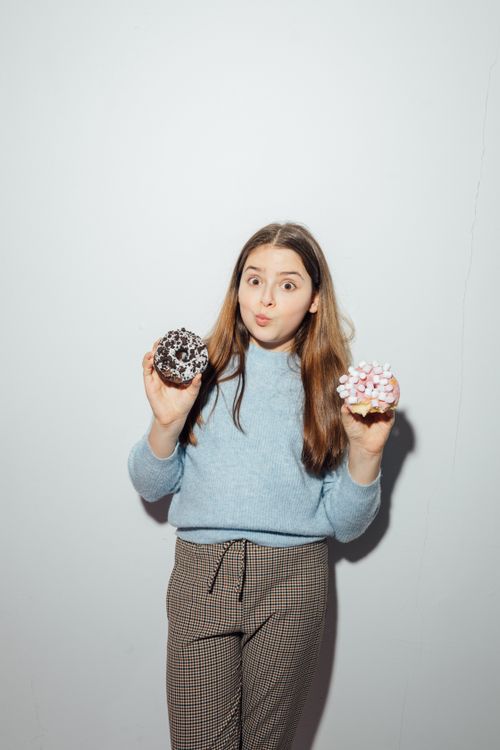 Free A happy girl playfully holding donuts with sprinkles, expressing joy and fun. Stock Photo