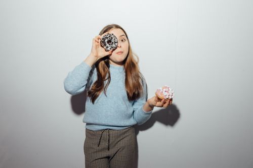 Free Young girl having fun with donuts, showcasing joyful expressions indoors. Stock Photo